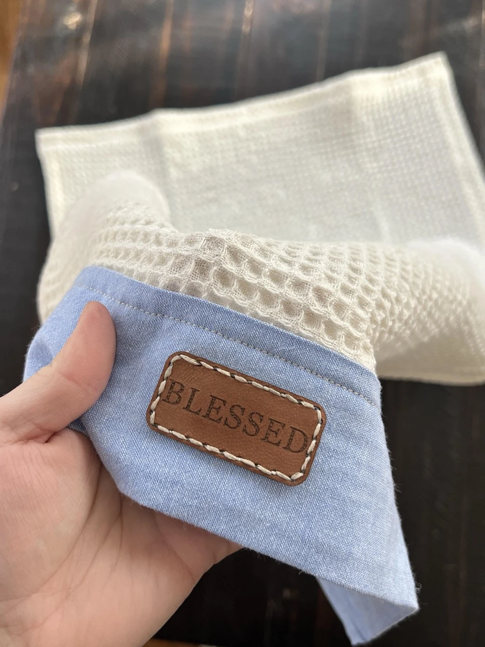 Close-up of the Blessed patch and contrasting stitches on the blue chambray towel border